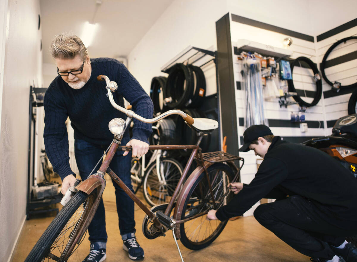 Två ur personalen reparerar en äldre cykel.
